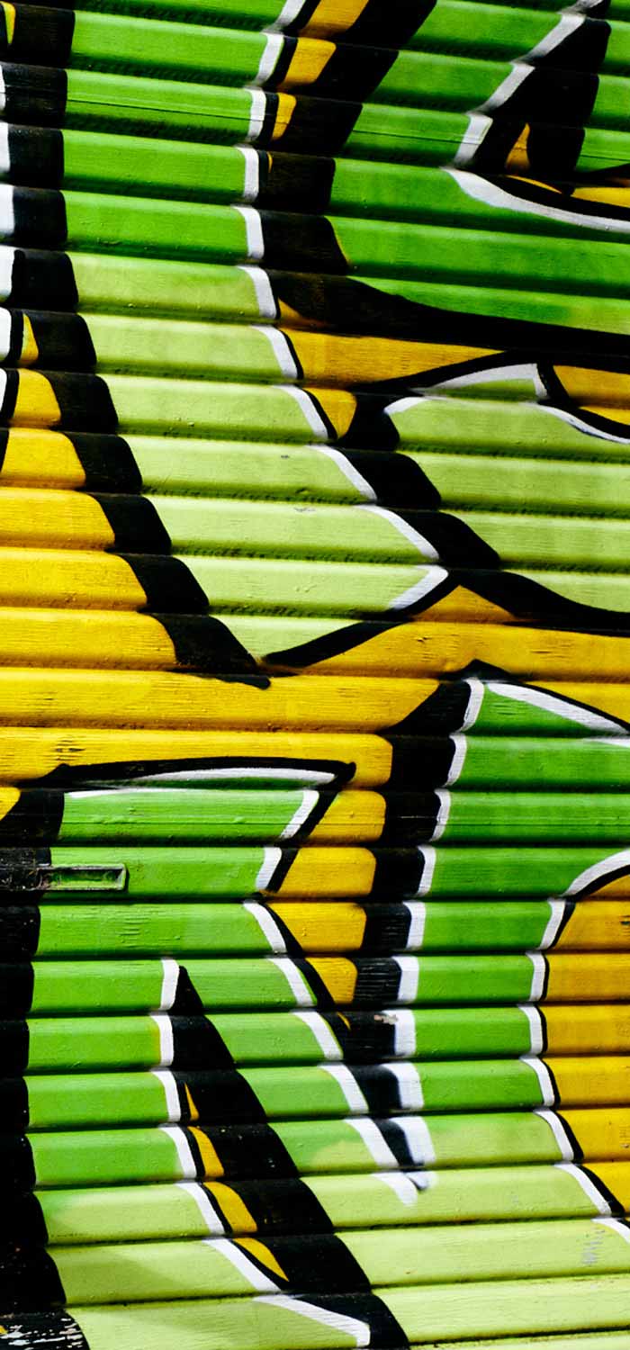 Graffiti wall in Melbourne with green writing on a yellow background.