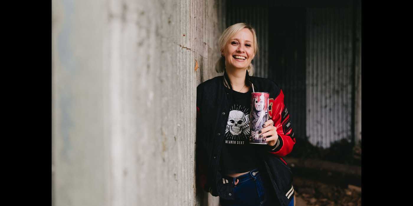 Cat Dunn OBM standing with a horror themed glass in her hand smiling