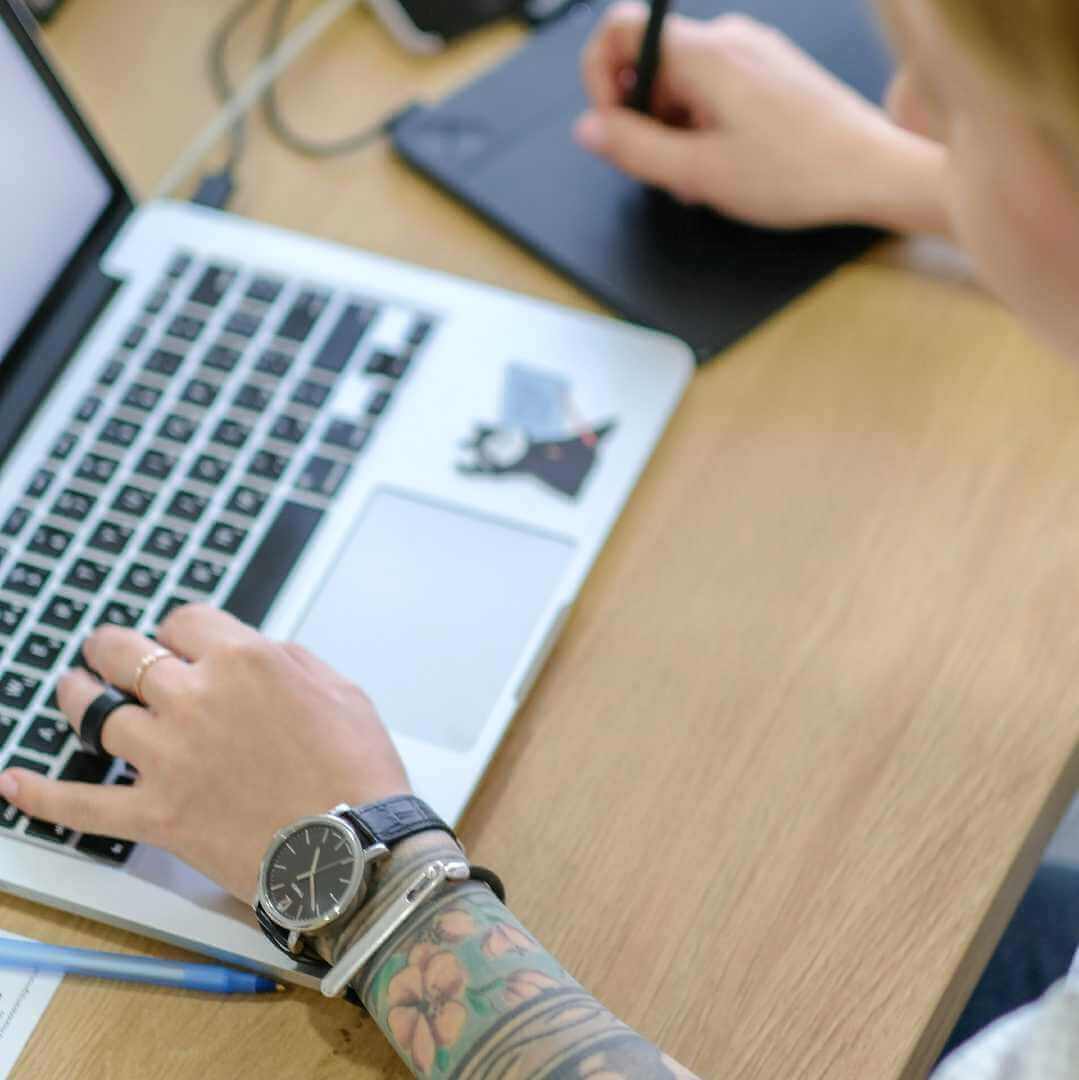 Person with tattooed arms working on a laptop