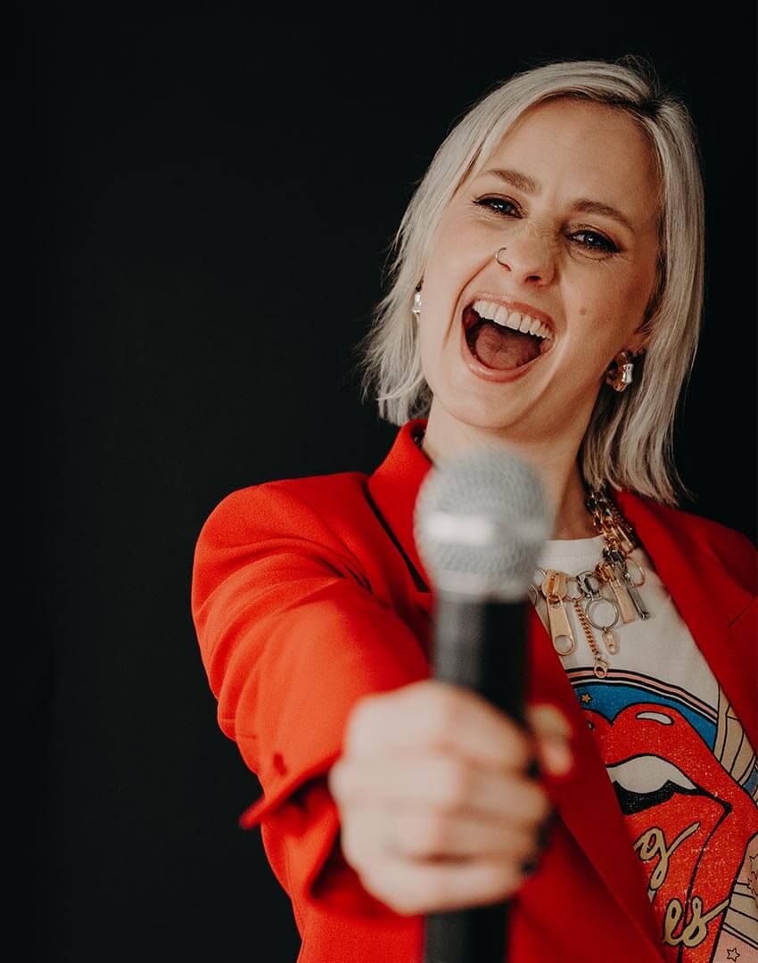 Female podcast guest holding a microphone out in front of her.