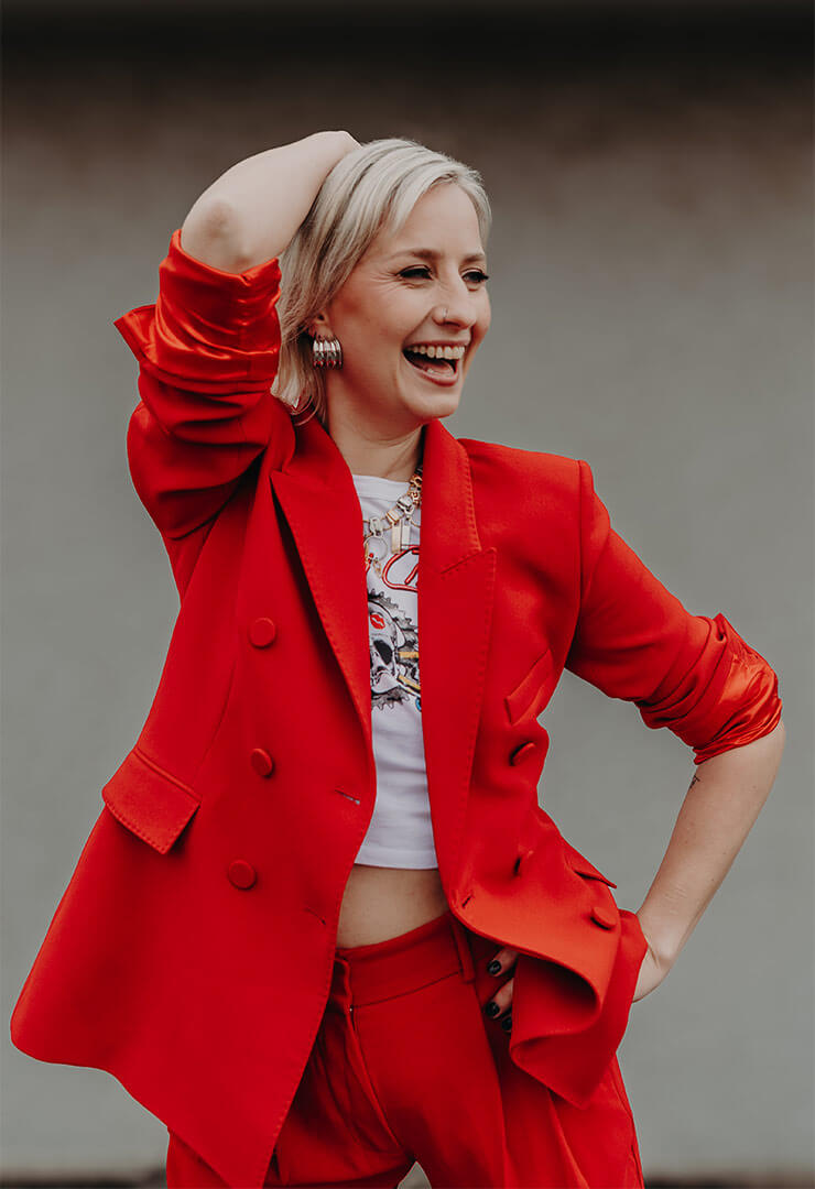 Australian OBM Cat Dunn, in a red suit and laughing.